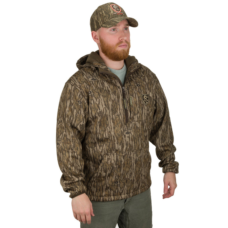 A man wearing a camouflage jacket and hat, featuring a deep quarter-zip neck and a vertical magnetic chest pocket. Ideal for cool fall days, this lightweight Endurance 1/4 Zip Jacket is made of polyester microfiber interlock fabric with Agion Active XL® scent control technology. Perfect for hunters seeking an advantage over game animals' sense of smell.