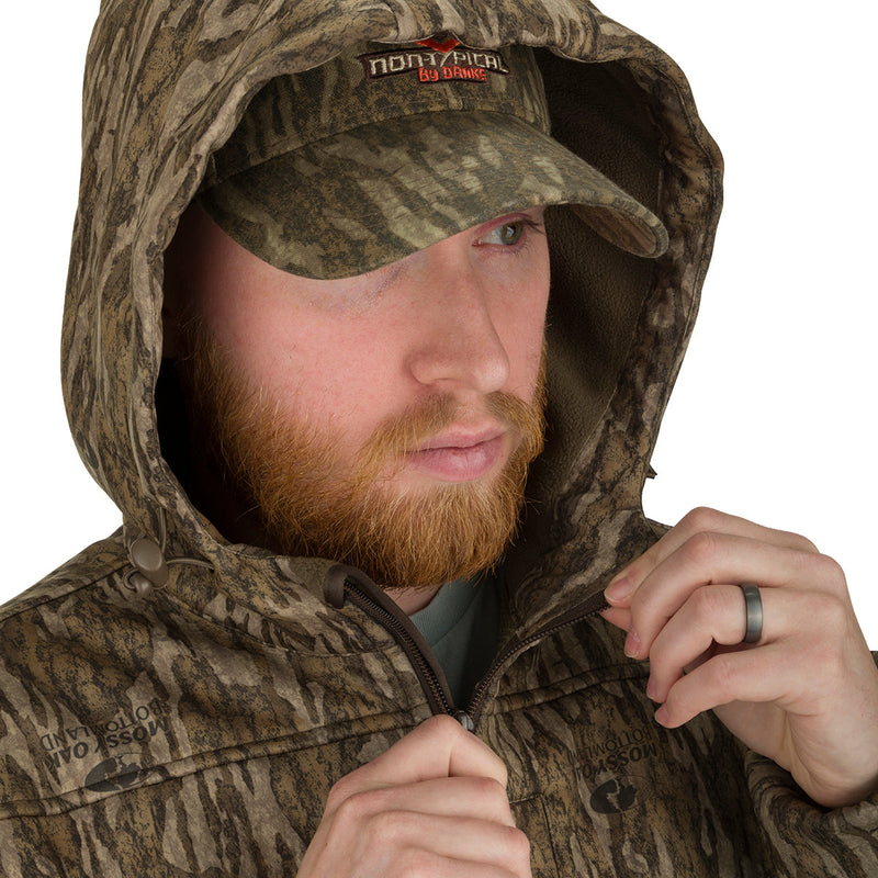 A man wearing the Endurance 1/4 Zip Jacket, a camouflage jacket and hat, showcasing the lightweight fabric and functional design for fall hunting. Features include a quarter-zip neck, magnetic chest pocket, and Agion Active XL® odor control technology.