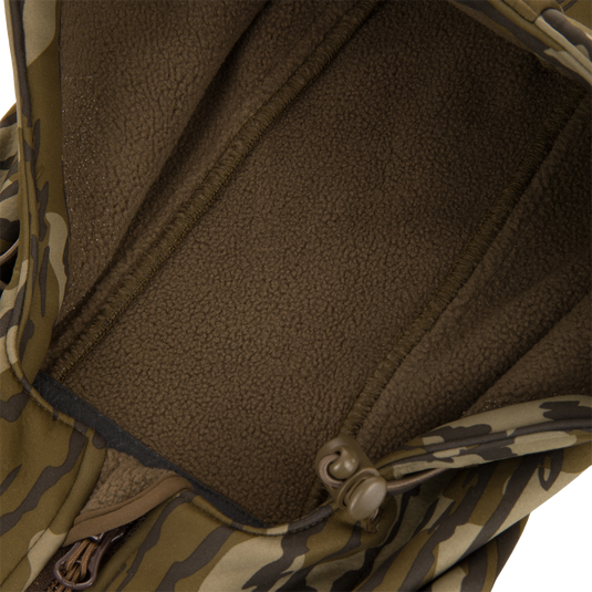 Youth Endurance Full Zip Jacket with Hood, featuring a camouflage outer shell, brown sherpa fleece lining, zipper pull, and drawstring toggle for flexible outdoor comfort.