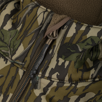 Close-up of a Nontypical Youth Endurance Full Zip Jacket with Hood featuring a green and brown tree bark camouflage pattern with a branded zipper pull.