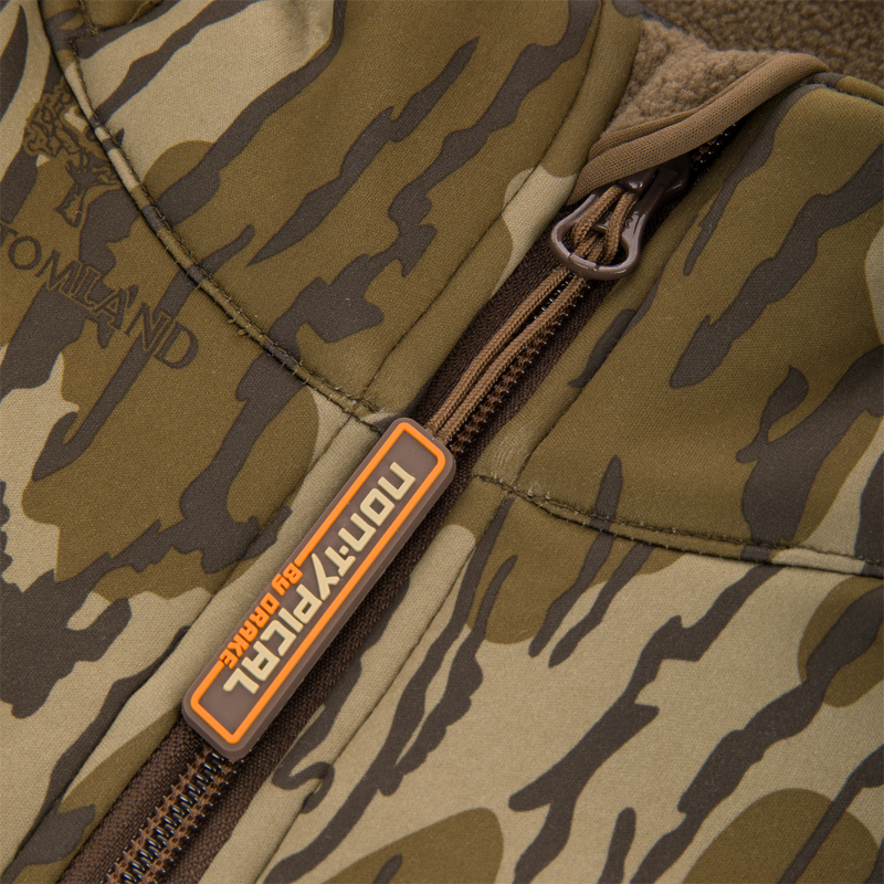 Youth Endurance Full Zip Jacket with Hood featuring camo pattern, central zipper, and rubber logo tag, designed for outdoor comfort with scent control and practical pockets.