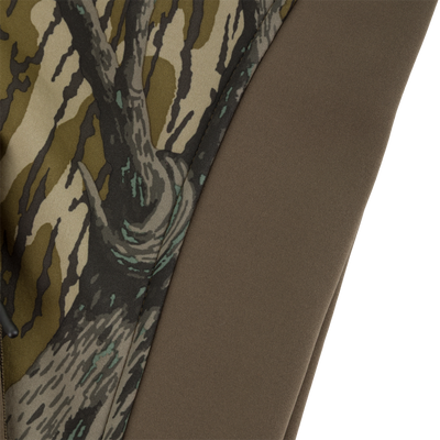 Close-up of a Youth Endurance Full Zip Jacket with Hood, featuring a tree bark camouflage pattern on one side and a solid brown, microfiber stretch fabric on the other.