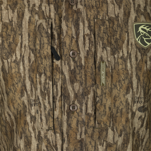 MST Microfleece Softshell Shirt - Realtree: A close-up of a shirt with logo, button, and black strap details. Features scent control technology, 7-button placket, gusseted underarm, and 4-way stretch. Two pockets for convenience.