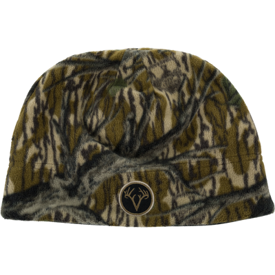 Non-Typical Windproof Fleece Beanie with Agion Active X2 in a dark forest camouflage pattern, featuring a circular patch with a deer antler logo on the front for added ear coverage.