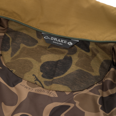 Delta Featherless Down Jacket interior showing camo lining, tan hood edge with green zipper, and C·DRAKE – Made in China label.