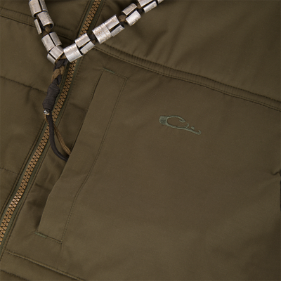 Close-up of the Delta Featherless Down Vest showing a brass-tone zipper, stitched pocket, embroidered logo, and braided cord with metal blocks, highlighting its functional design.