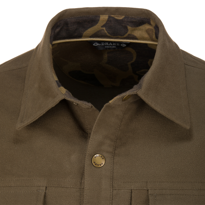 Close-up of the Delta Moleskin Shirt Jacket, showcasing the olive suede finish, camouflage-lined collar, “Drake” snap-button, and durable stitched detailing for hunting and outdoor wear.