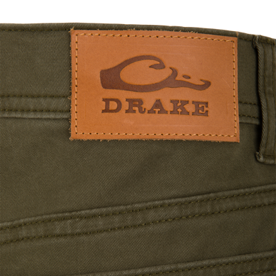 Olive green Wingshooter Twill 5 Pocket Pant featuring a brown leather patch on the back waistband embossed with a duck logo and the word DRAKE.
