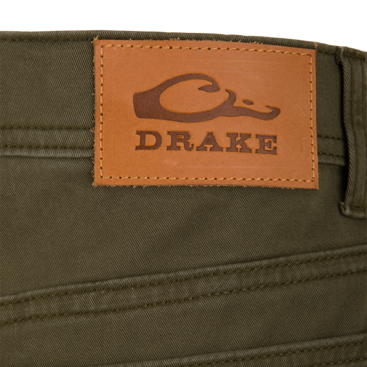 Olive green Wingshooter Twill 5 Pocket Pant featuring a brown leather patch on the back waistband embossed with a duck logo and the word DRAKE.