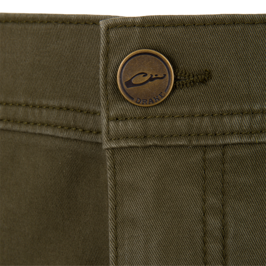 Close-up of olive green Wingshooter Twill 5 Pocket Pants featuring a brass-toned button embossed with a logo.