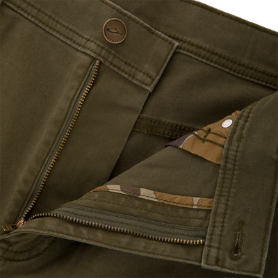 Olive green Wingshooter Twill 5 Pocket Pant featuring a zippered fly, a button closure, and camouflage-patterned fabric lining the inside of the waistband.