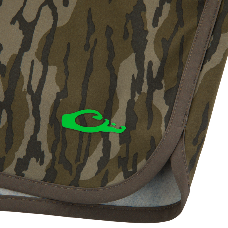 Close-up of Lake Shore Shorty Short's camo fabric, featuring neon-green logo and brown edging, highlighting its water-repellent, stretchable design for active water enthusiasts.