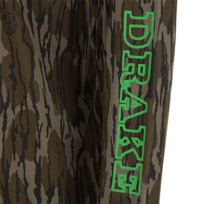 Lake Shore Performance Long Sleeve Hoodie featuring a brown/olive tiger-stripe camo pattern with a Mossy Oak logo, ideal for cooling and sun protection during outdoor activities.