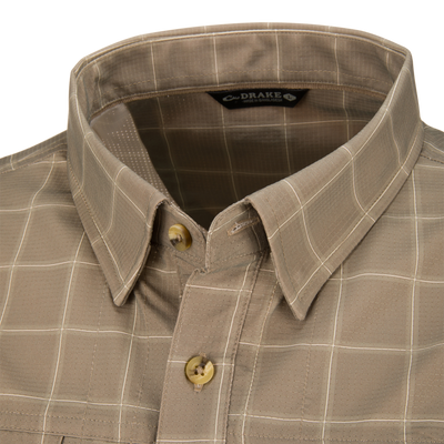 Close-up of a tan Wingshooter Hunter Creek Shirt featuring moisture-wicking fabric, a subtle white grid pattern, and a buttoned collar.