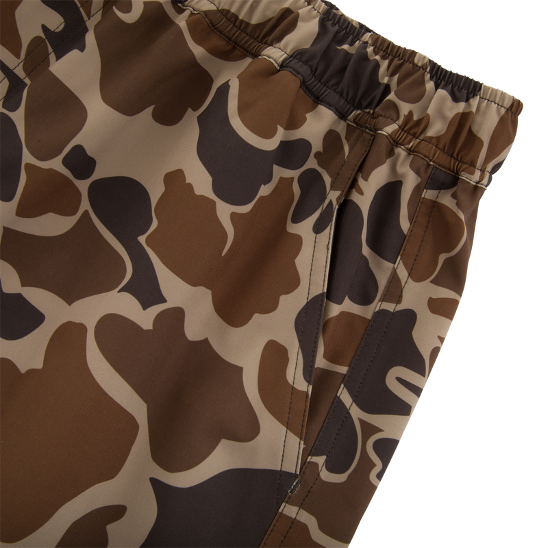 Americana Lake Shore Dock Short with elastic waistband, side zippered pocket, and brown camouflage pattern, ideal for water activities with lightweight, stretchable, water-repellent fabric.