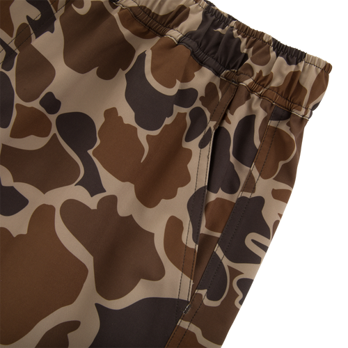 Americana Lake Shore Dock Short with elastic waistband, side zippered pocket, and brown camouflage pattern, ideal for water activities with lightweight, stretchable, water-repellent fabric.