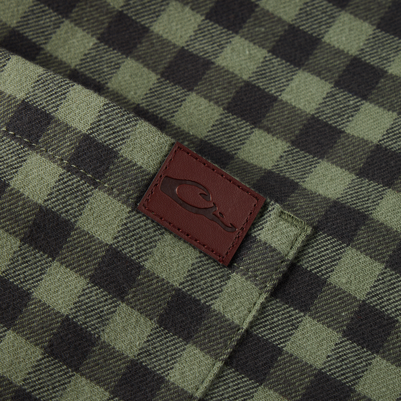 Close-up of the Autumn Flannel Shirt pocket, featuring a burgundy leather patch with logo, highlighting its brushed cotton twill fabric and outdoor-ready design.