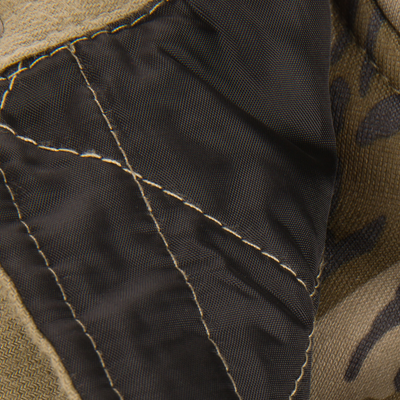 Close-up of The Youth Campfire Flannel Hoodie, highlighting quilted black nylon shell, beige fabric, and camouflage textile, suggesting durability and style for outdoor adventures.