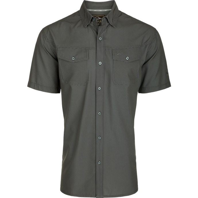 A close-up of the Traveler's Check Shirt S/S, a lightweight, breathable poly/spandex shirt with a hidden button-down collar and split tail hem. Ideal for the man on the go, it offers Four Way Stretch, sun protection, moisture-wicking, and quick-drying features.