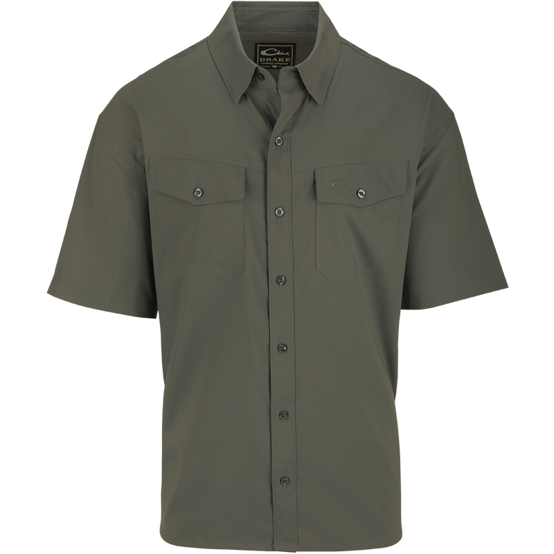A close-up of the Traveler's Solid Dobby Shirt S/S, featuring a hidden button-down collar, button-through chest pockets, and a split tail hem. Made with 100% Polyester dobby fabric, it offers UPF30 sun protection and moisture-wicking properties. Versatile for any season.