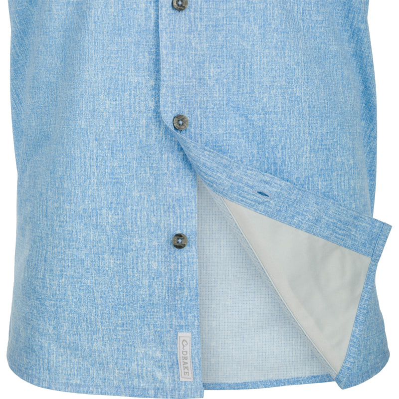 A blue and white short with buttons, made of lightweight polyester micro mesh for natural cooling and quick drying. Features include a hidden button-down collar, vented cape back, and two front chest pockets. Perfect for performance on the water or at the office.