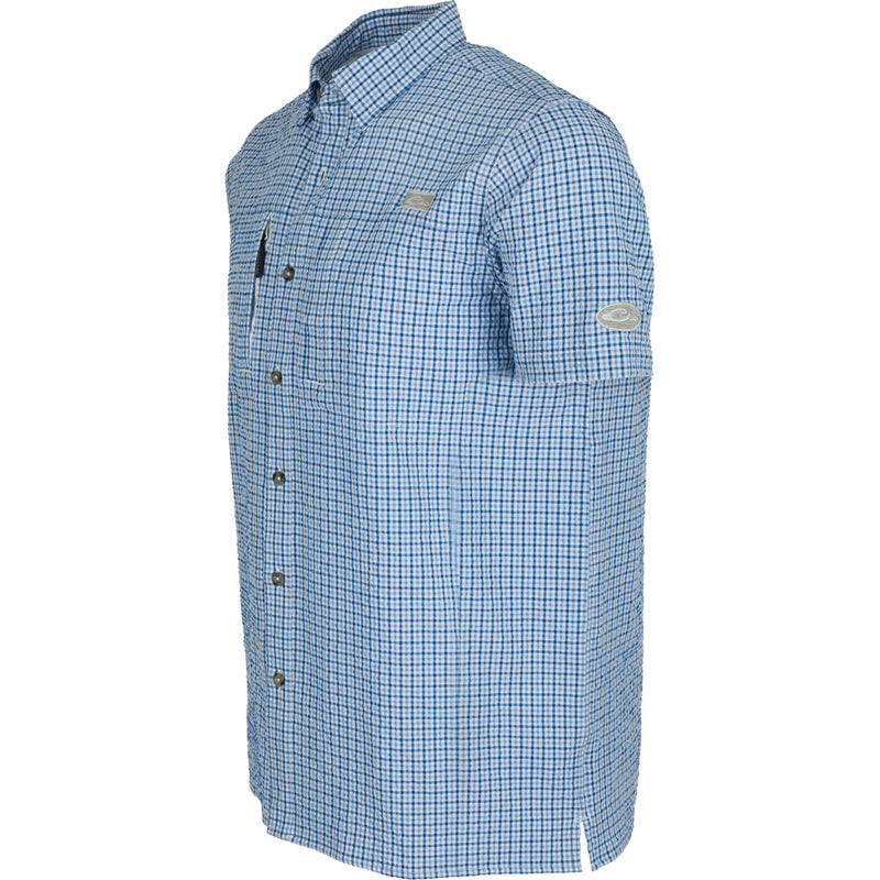 A close-up of the Classic Seersucker Grid Check Shirt, featuring a blue and white plaid pattern. Made from performance fabric with UPF30 sun protection, moisture-wicking, and quick-drying properties. Traditional hidden button-down collar, zippered chest pocket, and Magnattach™ closure. Vented cape back and split tail hem for added ventilation and versatility. Perfect for hunting, fishing, and casual wear.