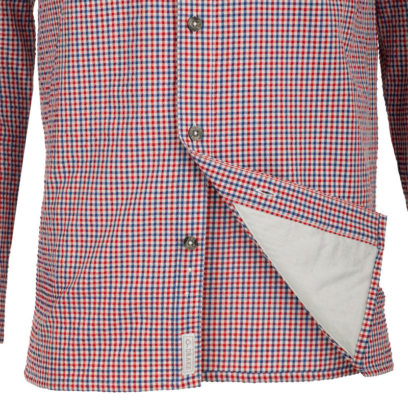 Classic Seersucker Grid Check Shirt L/S: A red and white checkered shirt with hidden button-down collar, zippered chest pocket, and Magnattach closure. Vented cape back and split tail hem for added ventilation. Moisture-wicking and quick-drying fabric with UPF30 sun protection. Adjustable roll-up sleeves with tab holder.