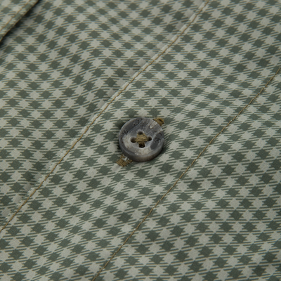 Close-up of the Frat Gingham Check Button-Down Long Sleeve Shirt, highlighting green-and-off-white houndstooth fabric with a four-hole button and visible stitching.