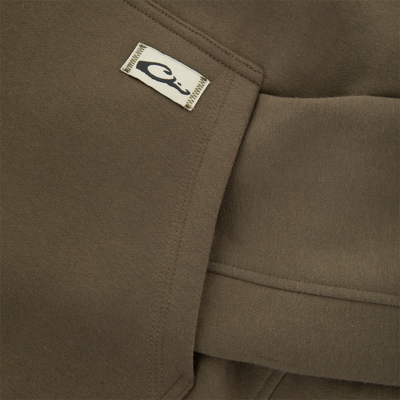 Close-up of The Three End Hoodie, highlighting a seam with a small cream fabric tag featuring a stylized C logo.