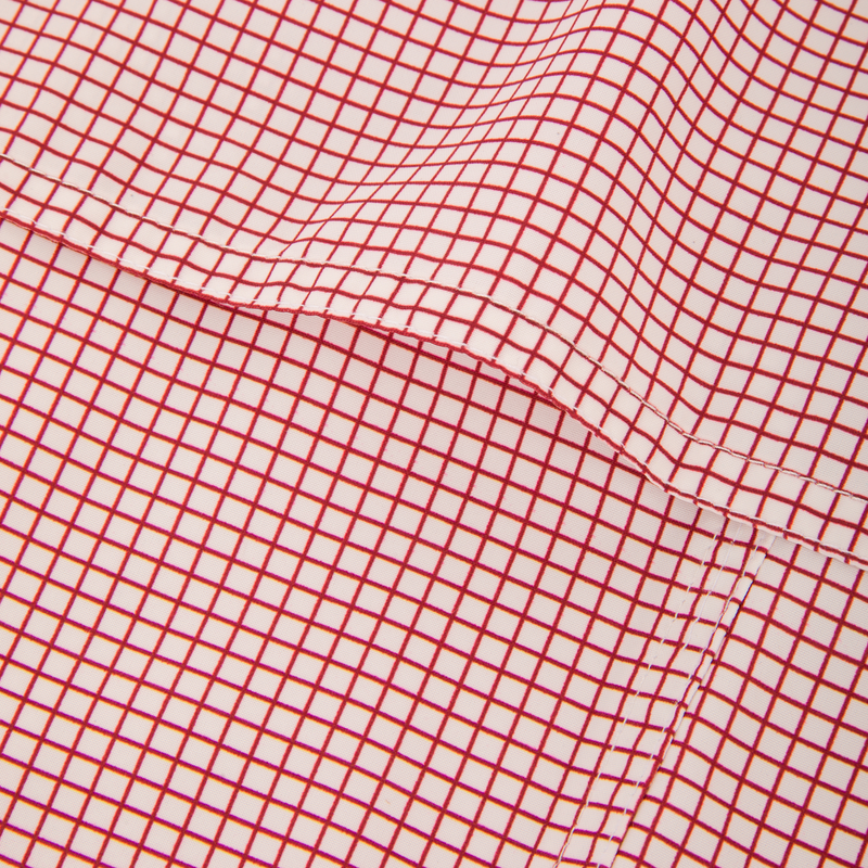 Close-up of Wingshooters Trey Grid Check Short Sleeve Shirt, featuring a fine red grid pattern on lightweight polyester with a stitched seam, highlighting its performance fabric.