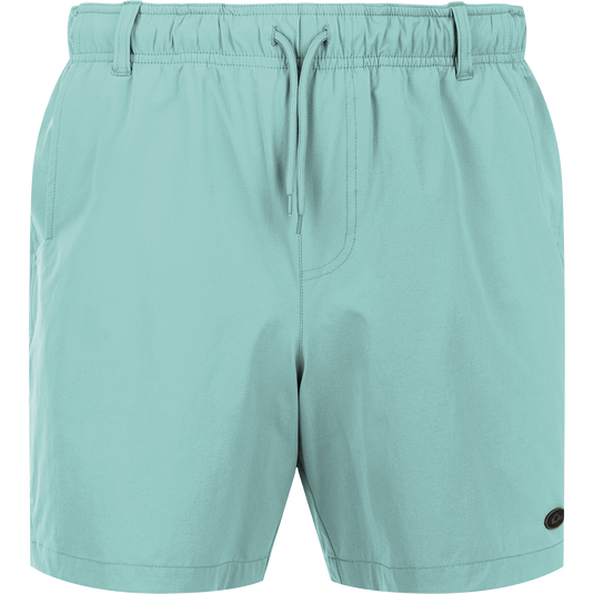 Dock Short 6" - A pair of light blue shorts with a close-up of a zipper. Made from durable 90% Nylon/10% Spandex fabric with a water-resistant finish. Features elastic waist, belt loops, and front/back mesh pockets. Perfect for boat to dock transitions.