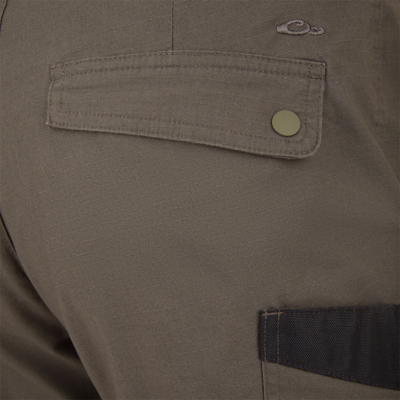 Close-up of the Drake 9-Pocket Ripstop Short, highlighting the snap-button flap pocket and contrasting black trim, showcasing durable ripstop fabric for outdoor adventures.