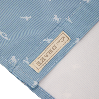 Close-up of Cinco Ranch Western Short Sleeve Shirt showcasing light blue fabric with tiny white dinosaur silhouettes, highlighting the stitching and beige cloth label.