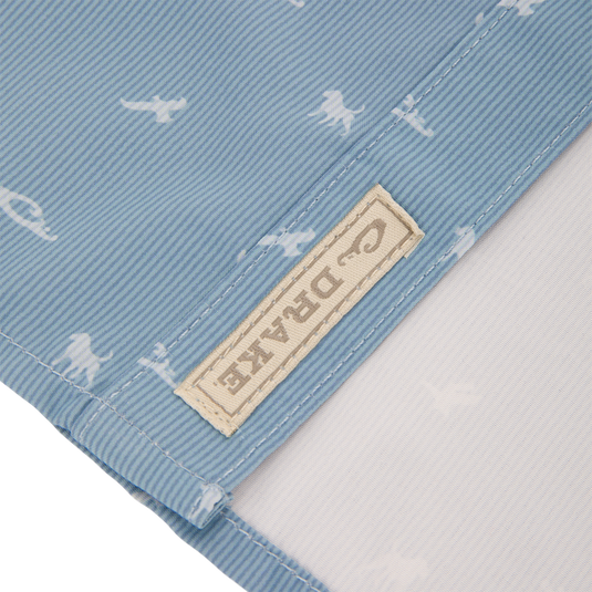 Close-up of Cinco Ranch Western Short Sleeve Shirt showcasing light blue fabric with tiny white dinosaur silhouettes, highlighting the stitching and beige cloth label.