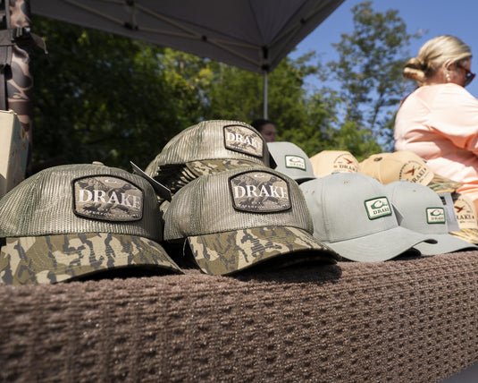 Drake x Lost Hat Ea5y Meshed Trucker Caps, featuring breathable mesh and adjustable snapback, displayed under a canopy, ideal for outdoor comfort.