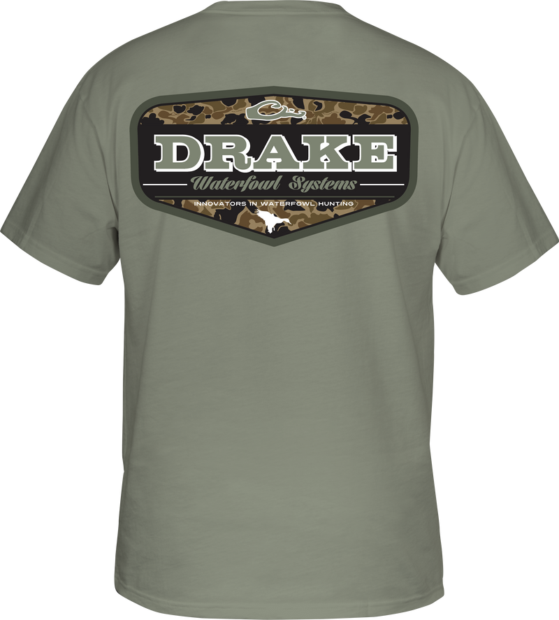 A grey shirt with a logo on the back, featuring a camouflage badge design.