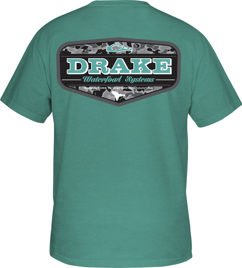 A green Old School Badge T-Shirt with a Drake logo on the front pocket. Made of a cotton/polyester blend for softness and comfort.
