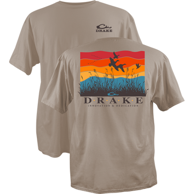 Flyway Sunrise Cotton T-Shirt with Drake logo on front; back features colorful marsh scene with ducks, grasses, and DRAKE above INNOVATION & DEDICATION slogan.