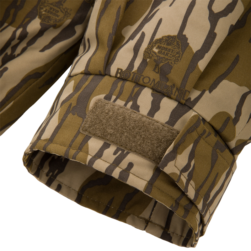 Throwback 80 Insulated Sport Bomber Jacket cuff in Bottomland camo, featuring Velcro strap and branded logo, showcasing durable design for hunting.