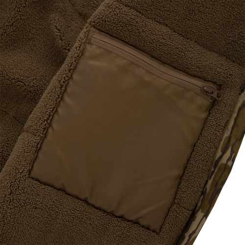 Close-up of the Throwback 80 Sport Vest's brown sherpa fleece with a zippered nylon pouch, showcasing its durable outdoor-ready design for hunting enthusiasts.