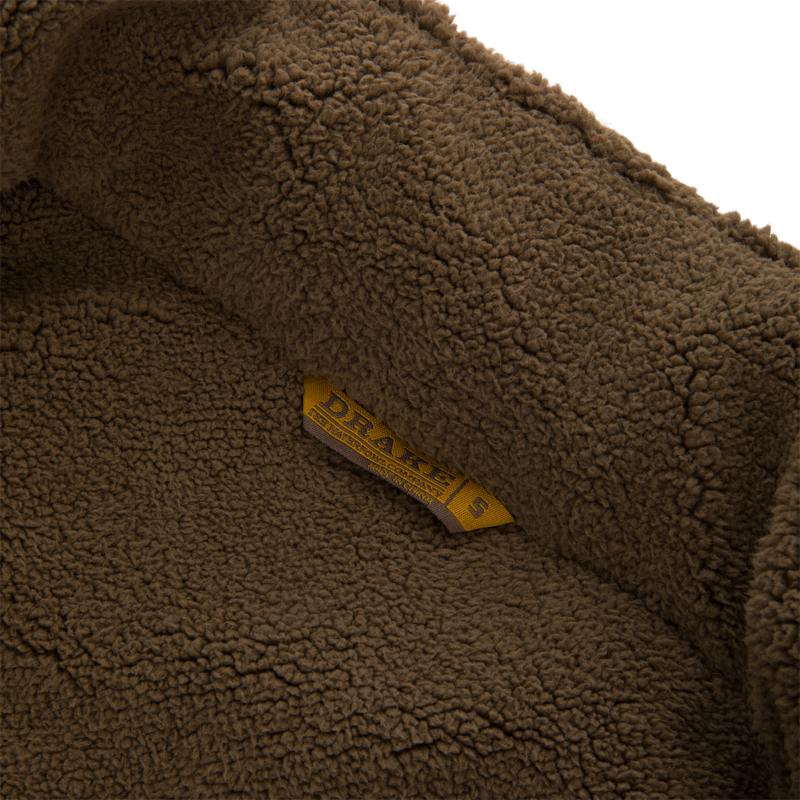 Close-up of the Throwback 80 Sport Vest's soft sherpa fleece lining with a DRAKE size tag, highlighting its warmth and comfort features for outdoor adventures.