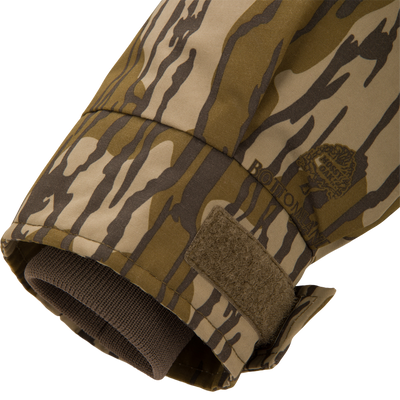 Close-up of the Throwback 80 Sport 3-in-1 Jacket's camo sleeve cuff, showing a tiger-stripe print, adjustable Velcro tab, and inner knit wrist gaiter.
