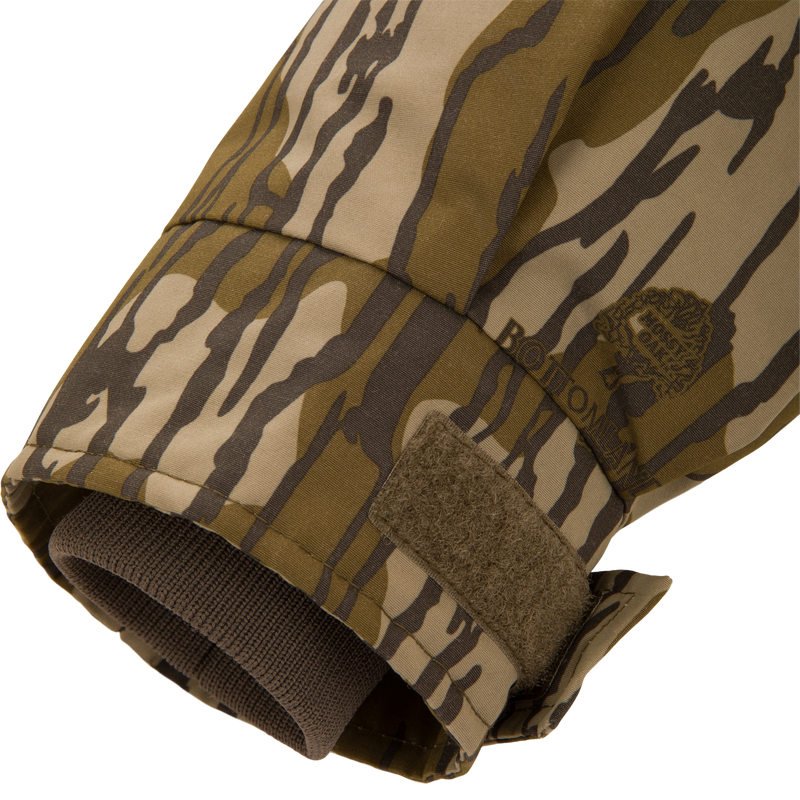 Close-up of the Throwback 80 Sport 3-in-1 Jacket's camo sleeve cuff, showing a tiger-stripe print, adjustable Velcro tab, and inner knit wrist gaiter.
