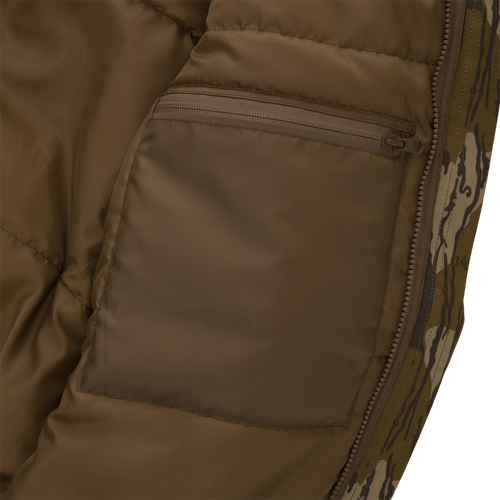 Close-up of Throwback 80 Sport 3-in-1 Jacket's interior, showcasing brown lining, internal zip-pocket, padded stitching, and edge of camo-patterned outer shell with main zipper.