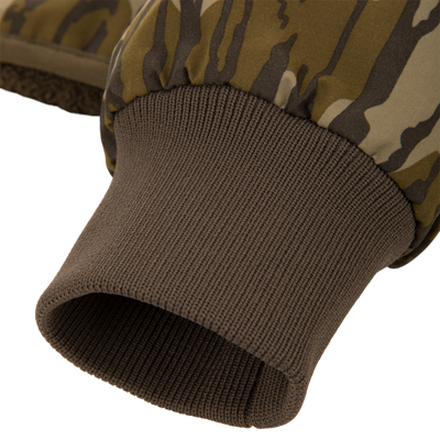 Close-up of a camo-patterned mitten's wrist area, showcasing the fleece lining and ribbed knit cuff, part of the Throwback 80 Sport 3-in-1 Jacket ensemble.