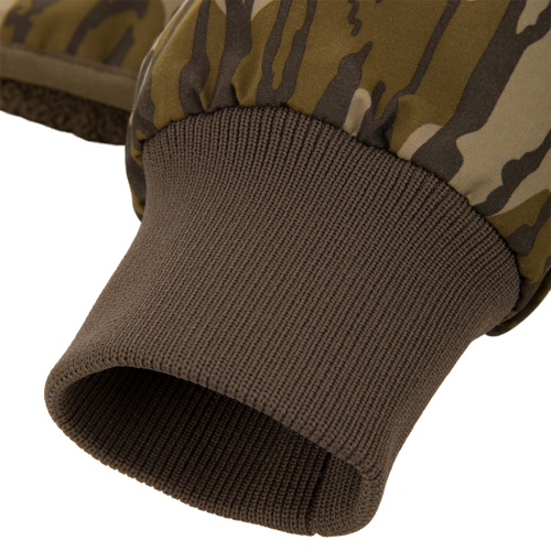 Close-up of a camo-patterned mitten's wrist area, showcasing the fleece lining and ribbed knit cuff, part of the Throwback 80 Sport 3-in-1 Jacket ensemble.