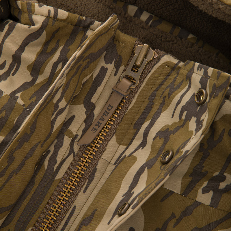 Close-up of the Throwback 80 Sport 3-in-1 Jacket's front placket, featuring a heavy-duty zipper, snap-fasteners, and tiger-stripe camouflage fabric with sherpa fleece lining.