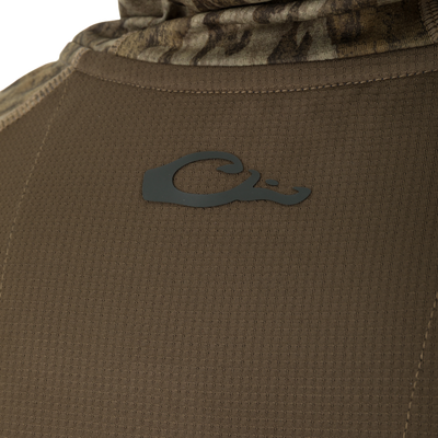Close-up of BMF EST Offset Quarter Zip Hoodie, showing olive-brown perforated fabric with camouflage hem and partial logo, highlighting tactical design and performance features.