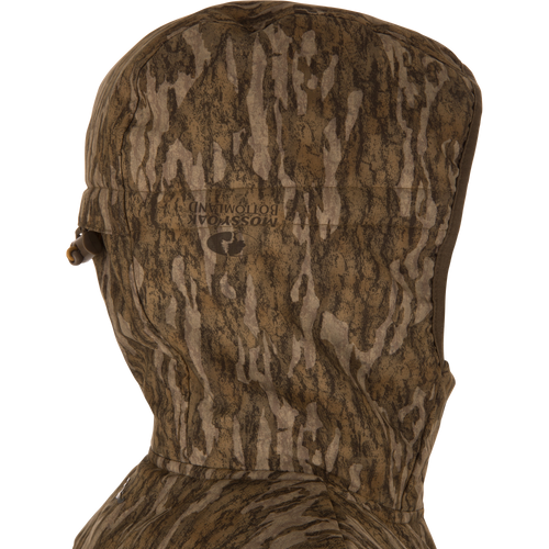 Close-up side view of LST BMF Jacket with Primaloft, showcasing a camouflage-patterned hood with adjustable draw-cord toggle and Mossy Oak Bottomland print.