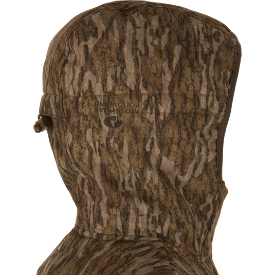 Close-up side view of LST BMF Jacket with Primaloft, showcasing a camouflage-patterned hood with adjustable draw-cord toggle and Mossy Oak Bottomland print.